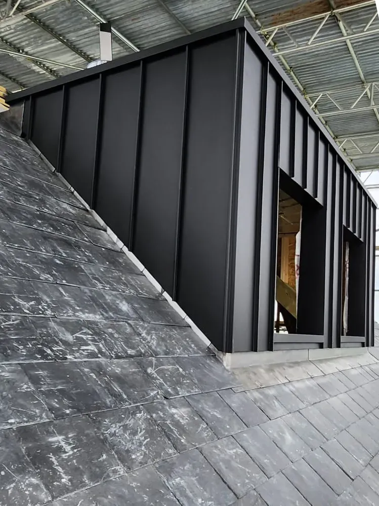 Dark aluminium standing seam cladding on a dormer with a recessed doorway