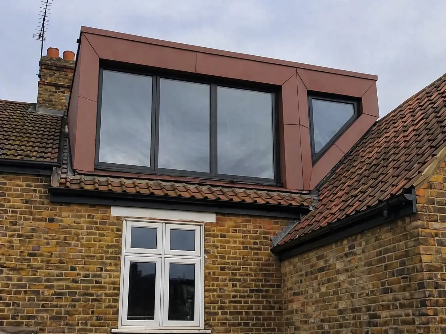 Red zinc dormer cladding with large corner windows on a pitched roof