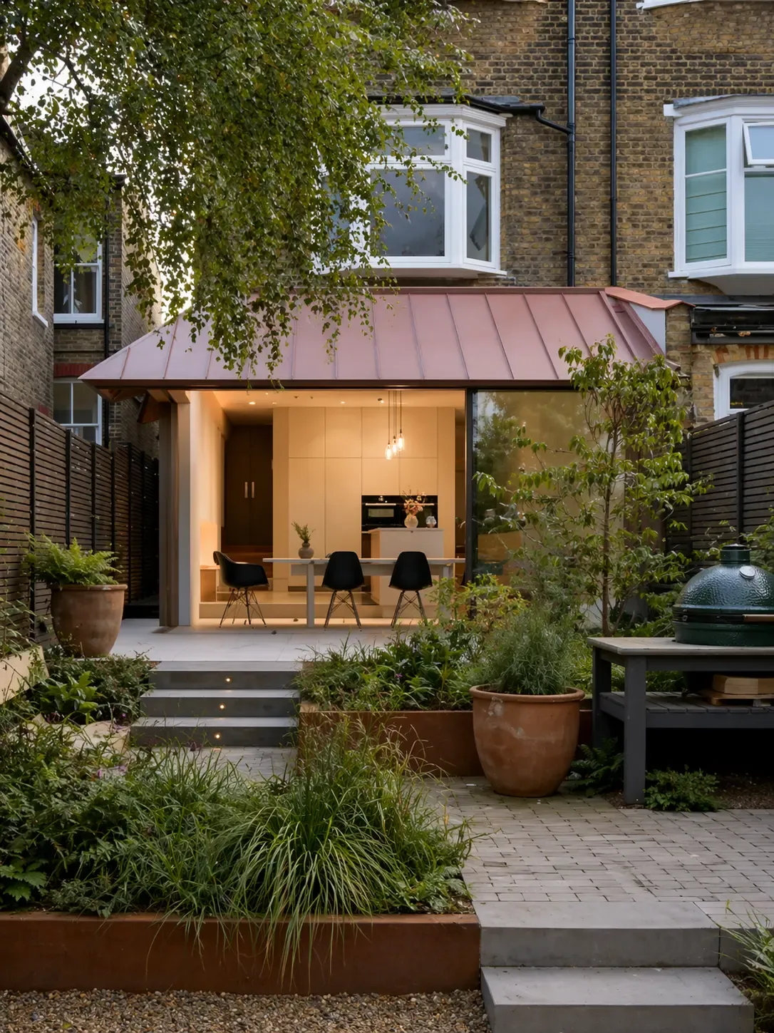 Copper-toned zinc canopy roof over a rear extension opening onto a garden