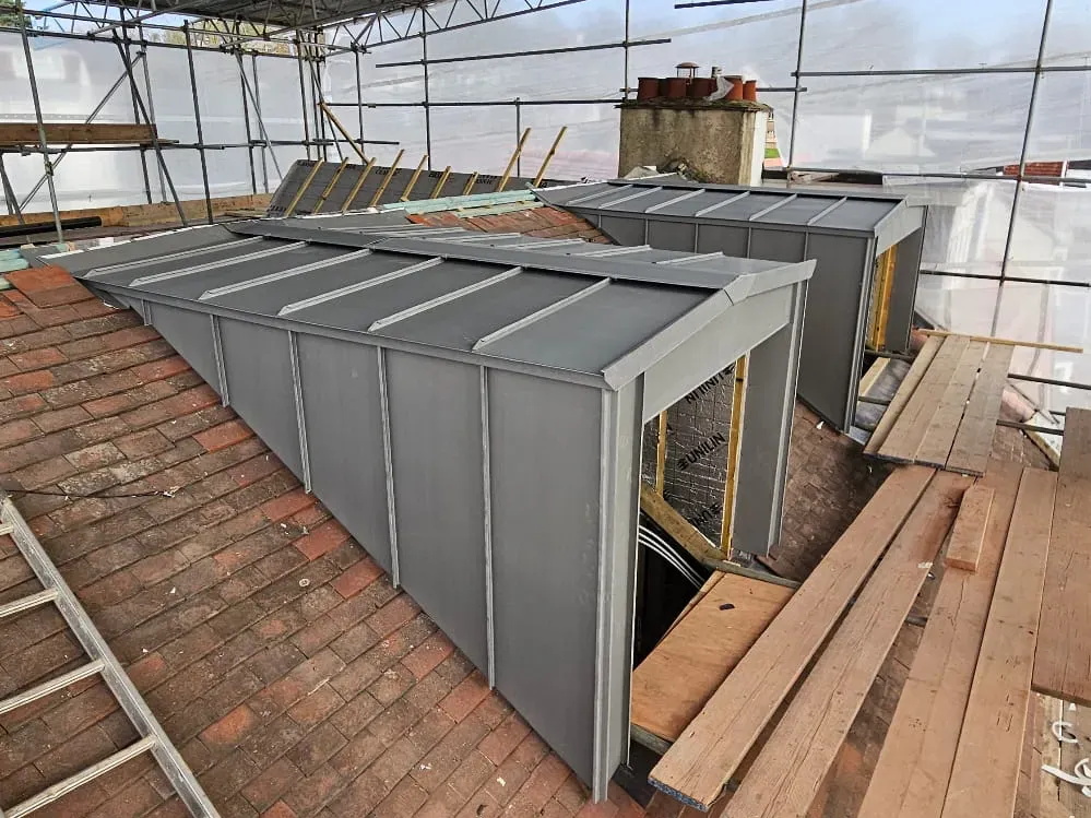 Zinc-clad box dormers under construction on an existing tiled roof