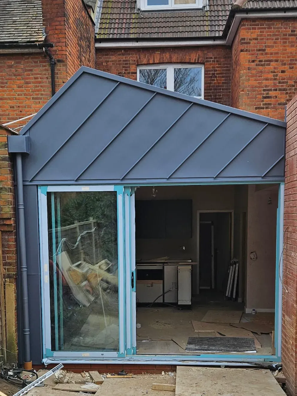 Zinc standing seam entrance canopy on a rear extension with sliding doors