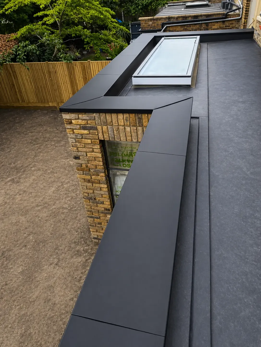 Aluminium coping and roof edge detail around a flat roof rooflight