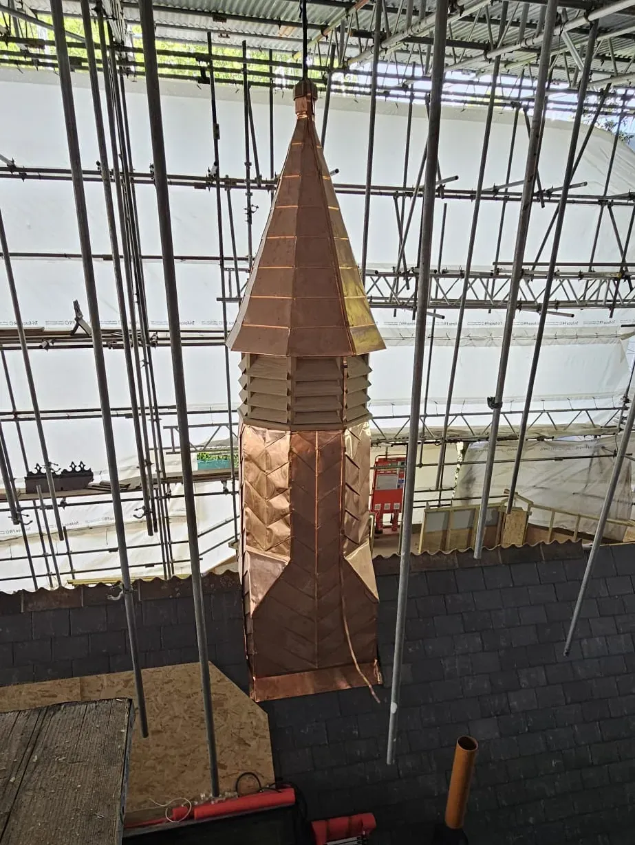 Tall copper spire under construction surrounded by scaffolding