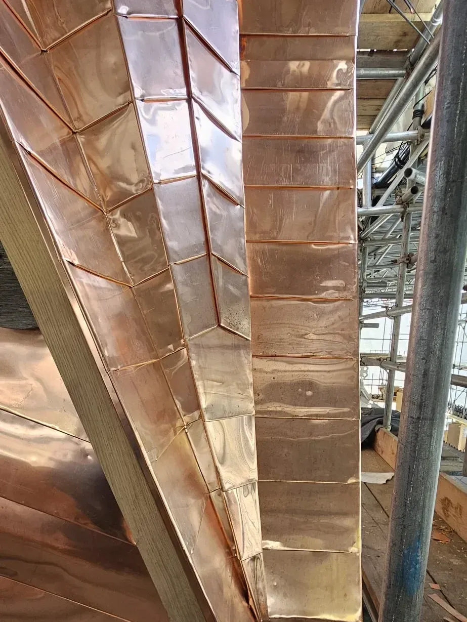 Close-up of folded copper standing seam detail on a tapered roof