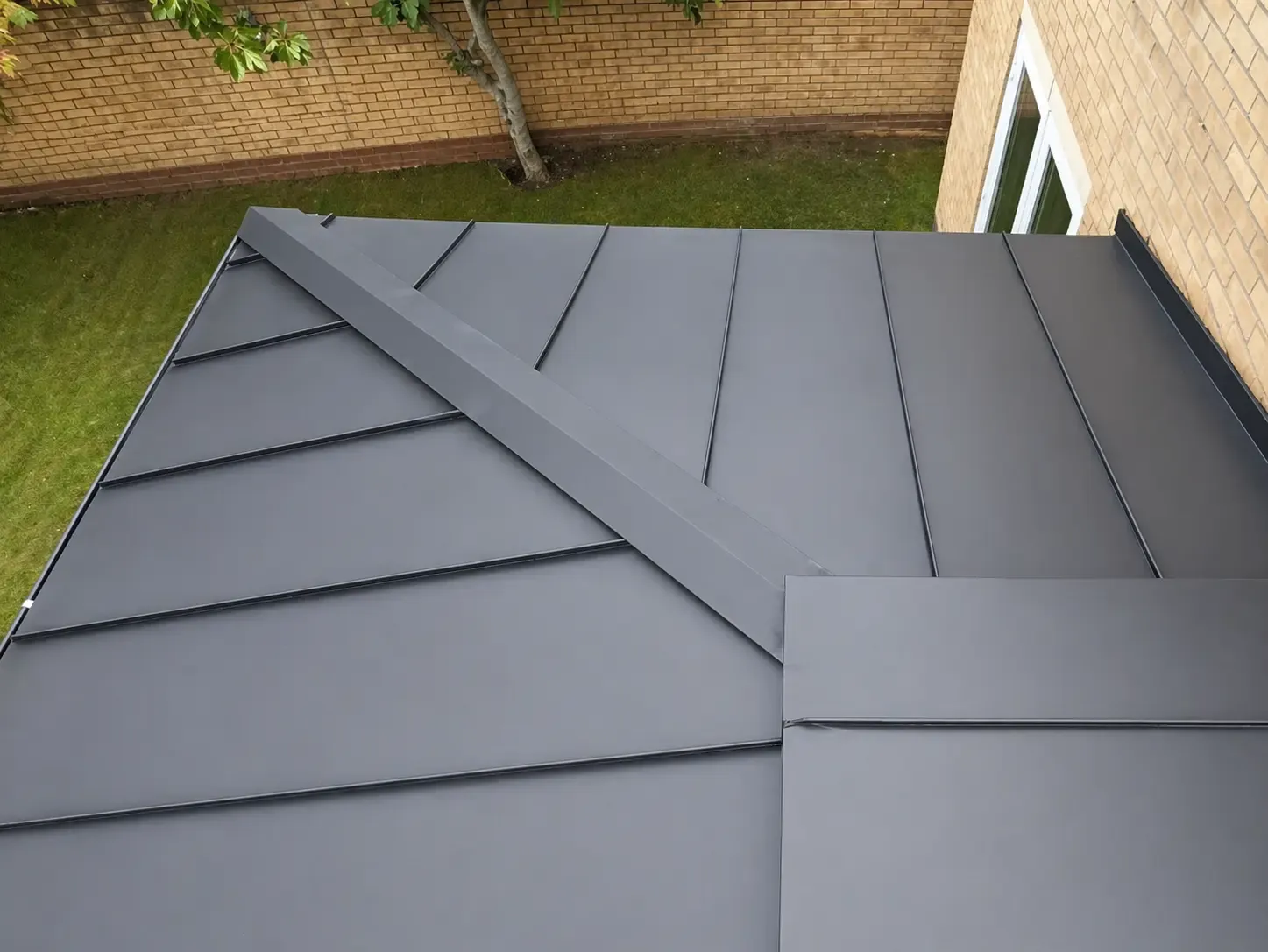 Zinc roof with diagonal standing seam pattern at a roof junction