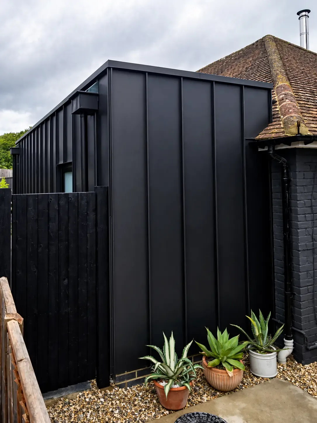 Dark zinc standing seam side extension with vertical cladding and folded roof