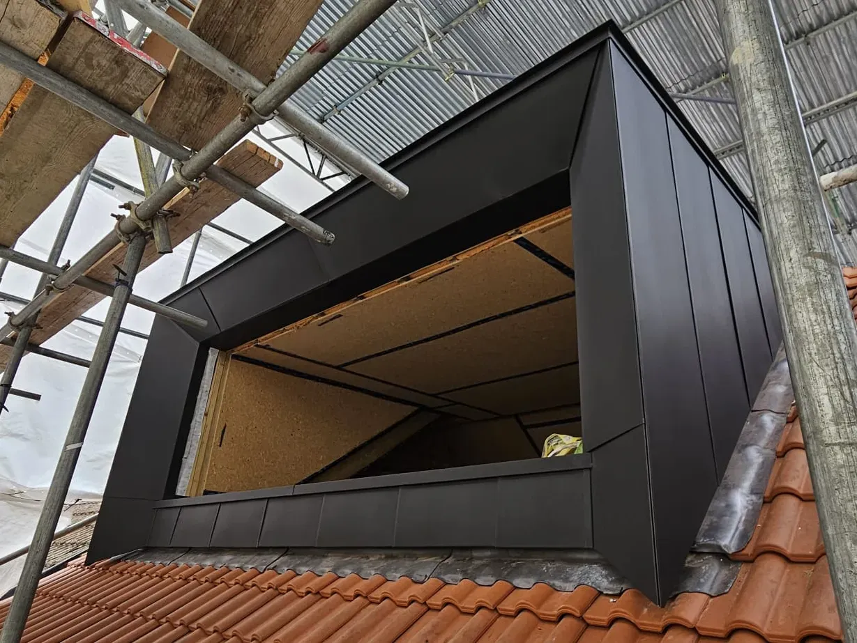 Dark zinc-clad dormer with deep window reveal under construction