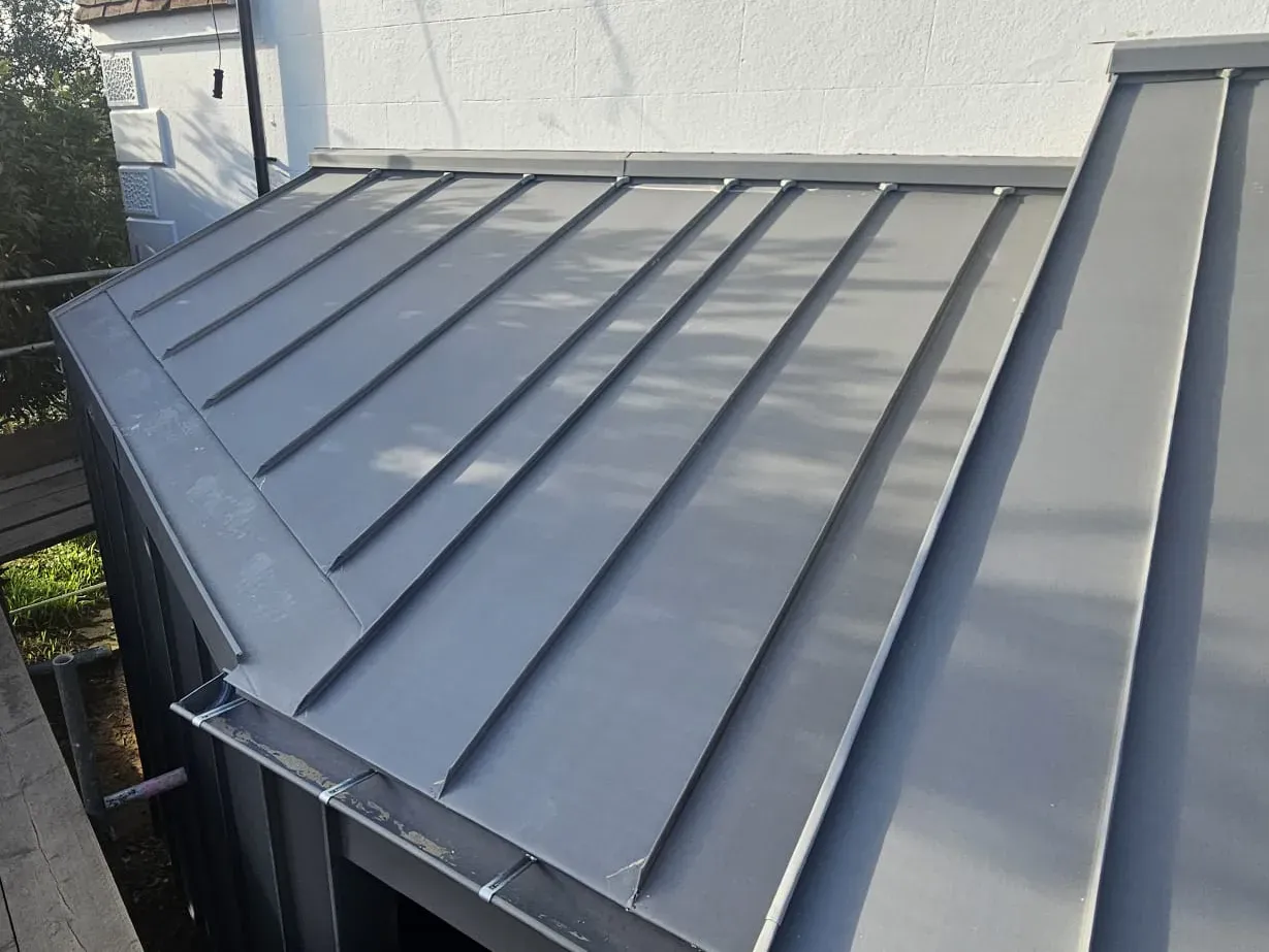 Grey zinc standing seam roof with raised seams and parapet edge detail
