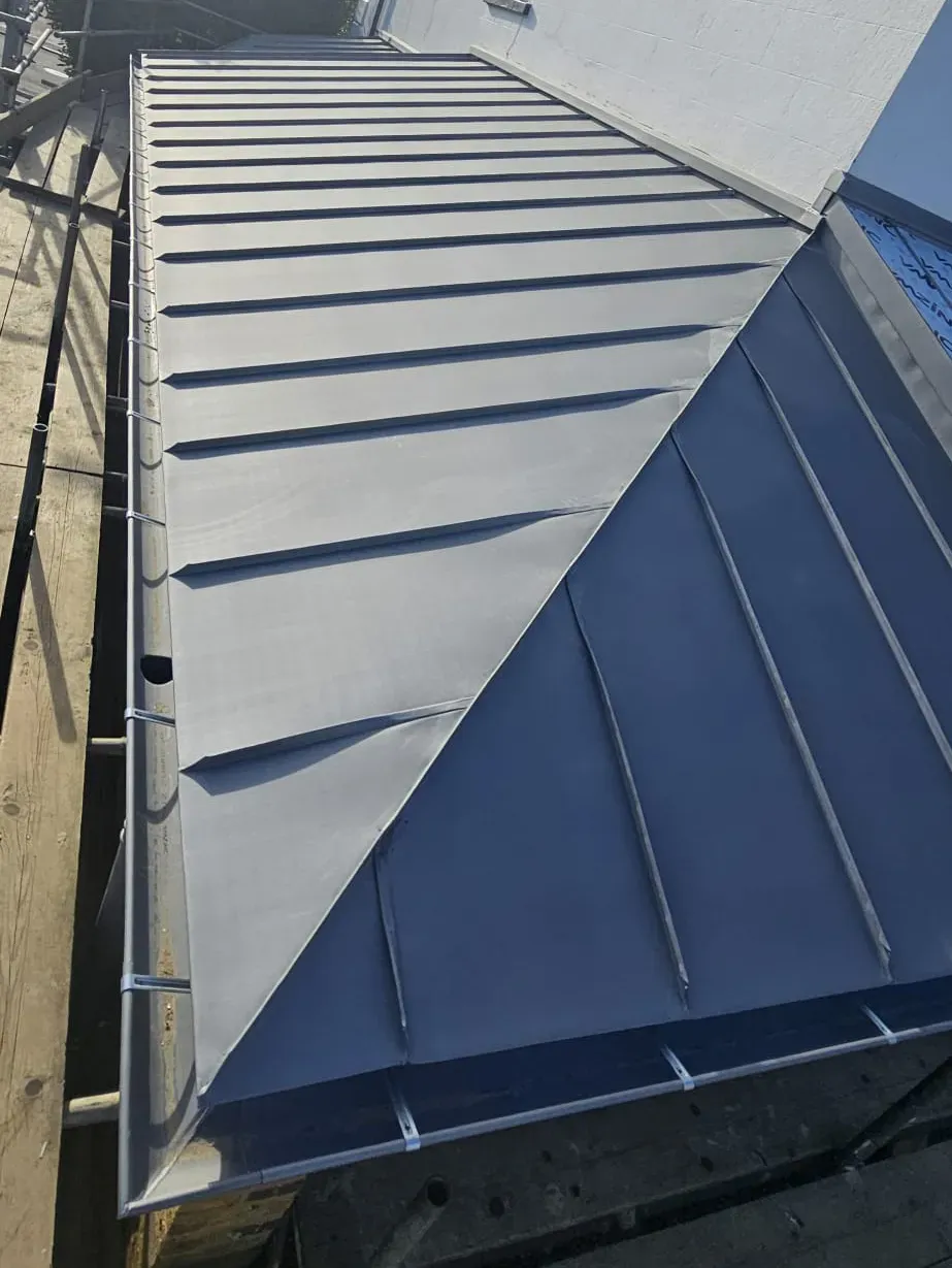 Dark zinc standing seam roof with narrow seam caps on a sloping section
